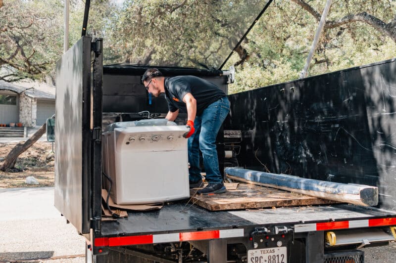 friendly junkstart junk removal employee loading washing machine onto truck