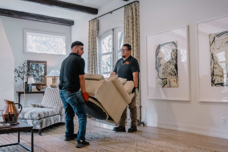 two friendly junkstart junk removal employees moving a couch in a san antonio home