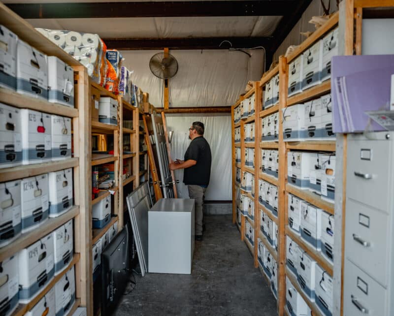 friendly junkstart junk removal employee moving doors in a well-organized storage unit