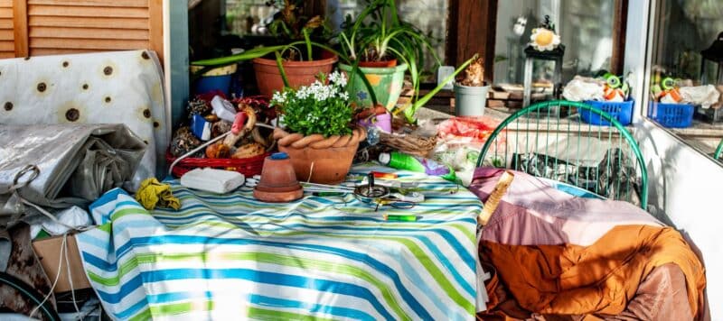 Cluttered patio area with a striped tablecloth, potted plants, and various gardening tools and items