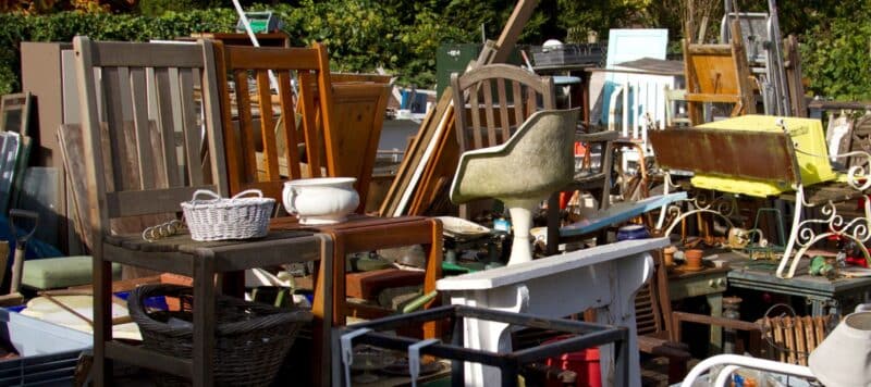 various chairs, furniture, and other old items sitting in a home's front yard