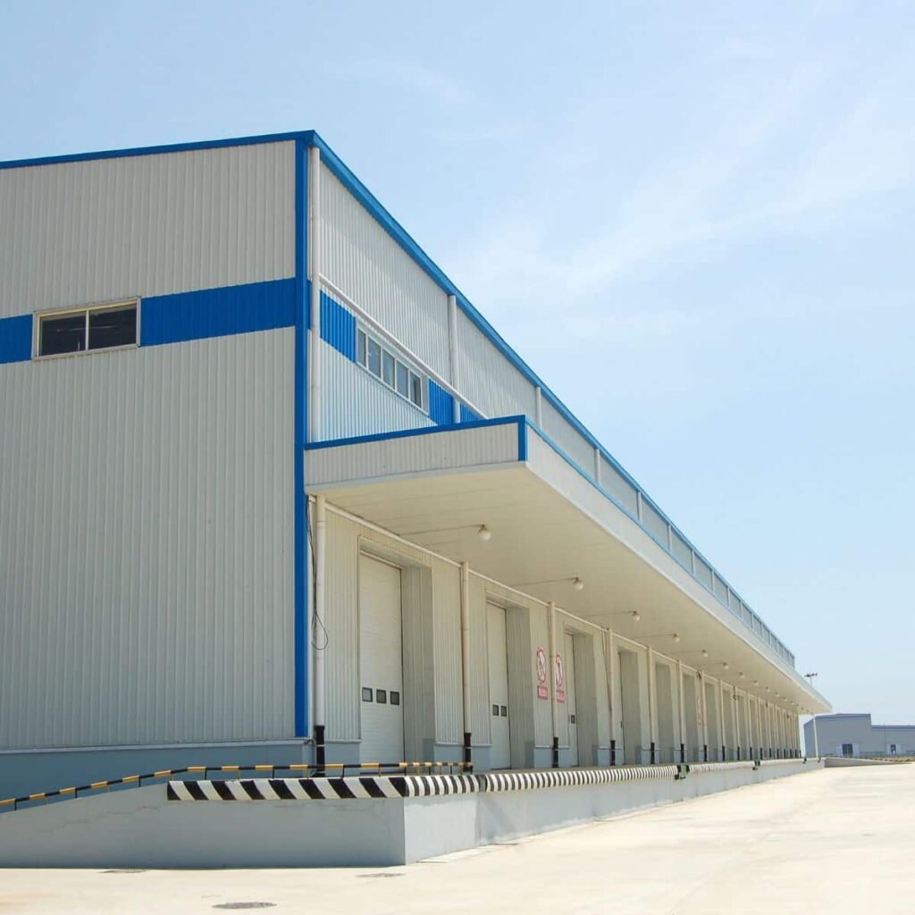 side view of a large white and blue striped warehouse with lots of bay doors