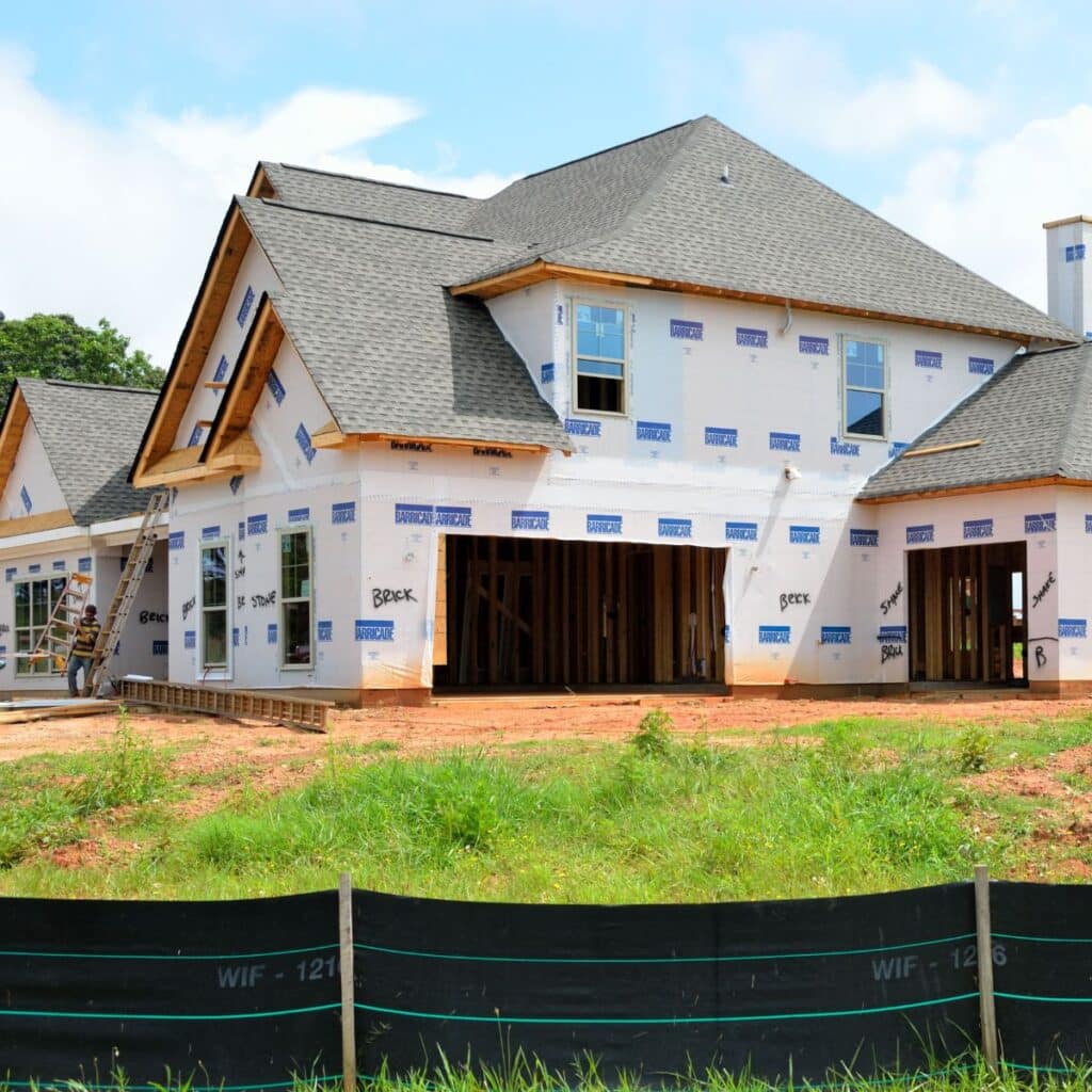 A new residential home under construction with exposed framing and house wrap
